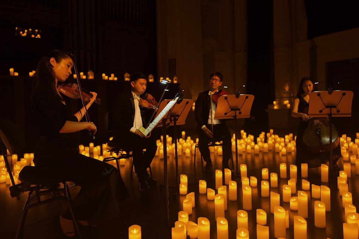 Musicians with stringed instruments surrounded by candles